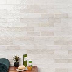 a wooden table topped with green towels next to a white tiled wall