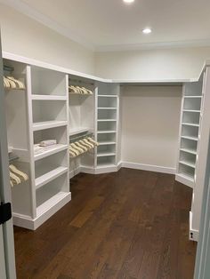 an empty walk in closet with white shelving and wood flooring on the hard wood floor