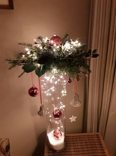 two pictures of christmas decorations in vases on a table with candles and ornaments hanging from the top