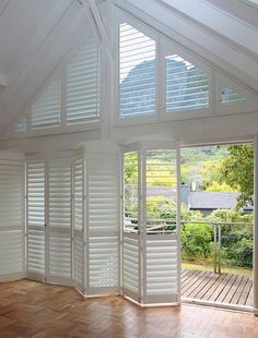 an empty room with wooden floors and white shutters