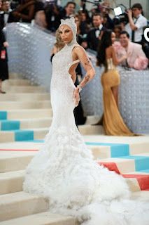 a model walks down the runway in a white gown with an elaborate cat head on top