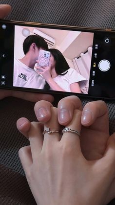 a person holding a cell phone taking a photo with their wedding ring on the finger