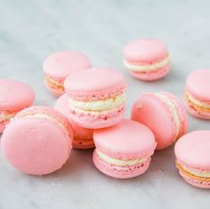 pink macaroons with white frosting on a marble surface