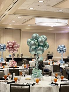 balloons are set up in the middle of a banquet room with tables and chairs around them