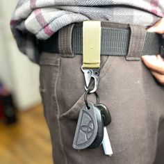 a person wearing a belt with two keys attached to the back of their pants and holding a cell phone in his pocket