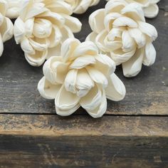 some white flowers are sitting on a wooden table and ready to be used as decorations