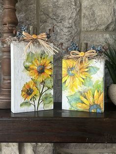 two sunflowers are painted on small bags sitting on a shelf in front of a stone wall