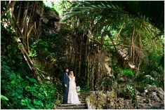 a bride and groom standing on steps in the jungle