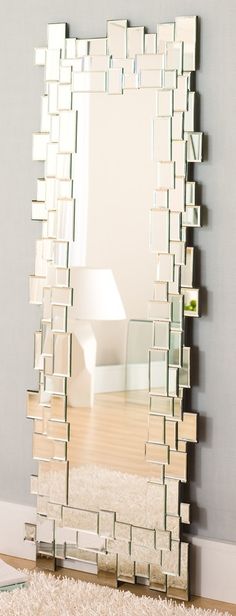 a mirror sitting on top of a wooden floor next to a white rug and wall