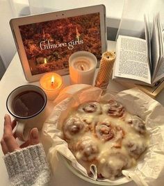 a person is holding their hand over a plate of food and an open book on the table