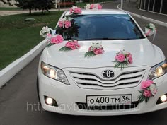 a white car decorated with pink flowers and ribbons