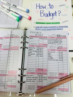 a binder and pen sitting on top of a paper with budget sheets next to it