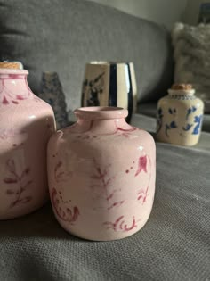 two pink vases sitting next to each other on a couch