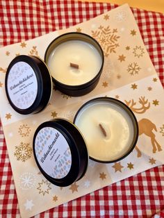 three candles sitting on top of a red and white checkered tablecloth with snowflakes