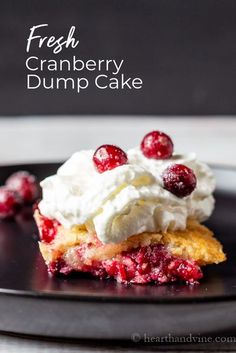 fresh cranberry dump cake on a black plate with whipped cream and cherries