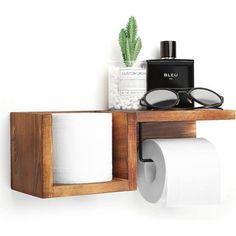 a wooden shelf with two rolls of toilet paper and some glasses on top of it