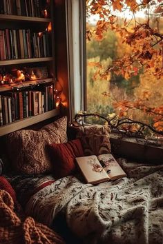 an open book sitting on top of a bed next to a window filled with books