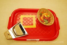 a red tray with a brush and some flowers on it