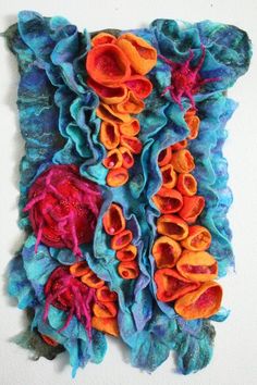 a piece of art that is made out of yarn and felt with flowers on it