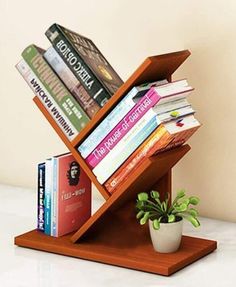 a book shelf with books and a potted plant in it on a white table