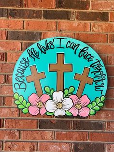 a sign on the side of a brick building with flowers and crosses painted on it