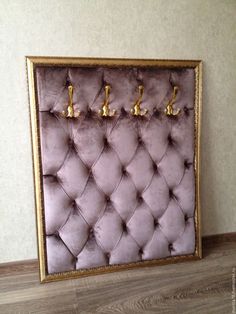 a purple velvet upholstered wall with gold trimmings and three golden faucets