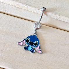 a blue and pink earring with a small cartoon character on it's side