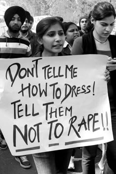 a woman holding a sign that says don't tell me how to dress tell them not to rage