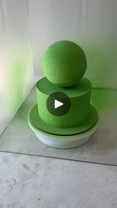 three green balls stacked on top of each other in front of a white wall and floor