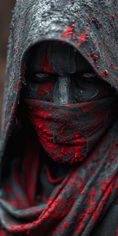 a person with black and red paint on their face, wearing a hooded cloak over his head