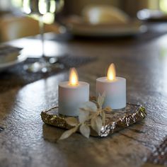 two white candles sitting on top of a wooden table