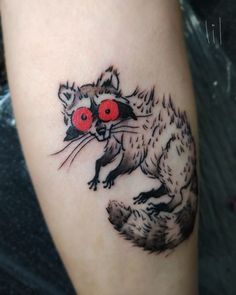 a raccoon tattoo with red eyes on the arm and leg, it looks like he is holding something in his hand