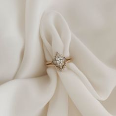 a diamond ring sitting on top of a white satin fabric with a knot in the middle