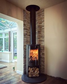 a wood burning stove in a living room next to a large glass window and wooden floor