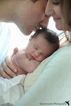 a man and woman holding a baby in their arms