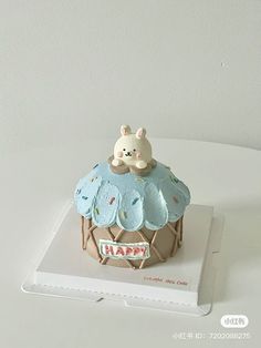 there is a small cake on top of the table with a teddy bear sitting on it