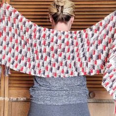 a woman standing in front of a wooden door wearing a red and white knitted sweater