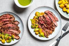 two plates with steak and vegetables on them next to a bowl of broccoli