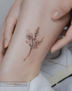 a woman's foot with a small flower tattoo on her left side ribcage