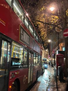 two red double decker buses parked next to each other on the side of a street