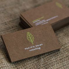 two brown business cards sitting on top of a cloth covered tablecloth with the words pacific point consulting printed on them