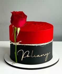 a red rose sitting on top of a black and white cake with writing on it