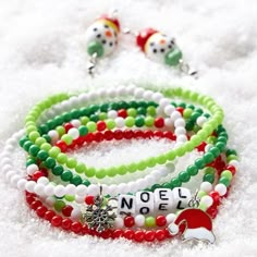 three bracelets with beads and charms on top of snow covered ground next to each other