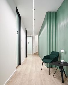 a green chair sitting next to a black table on top of a hard wood floor