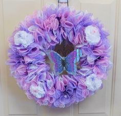 a purple and white wreath with a butterfly on it hanging from the front door,