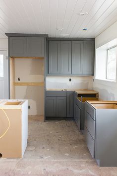 an unfinished kitchen with gray cabinets and wood flooring