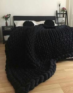 two beds covered in black blankets sitting on top of a wooden floor