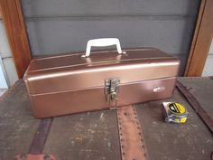 a brown suitcase sitting on top of a piece of luggage next to a can of beer