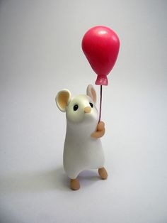 a small toy mouse holding a red balloon