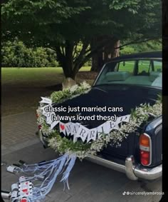 a wedding car decorated with white flowers and greenery is parked on the side of the road